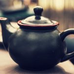 Schwarze Keramik-Teekanne liegt auf dem Tisch